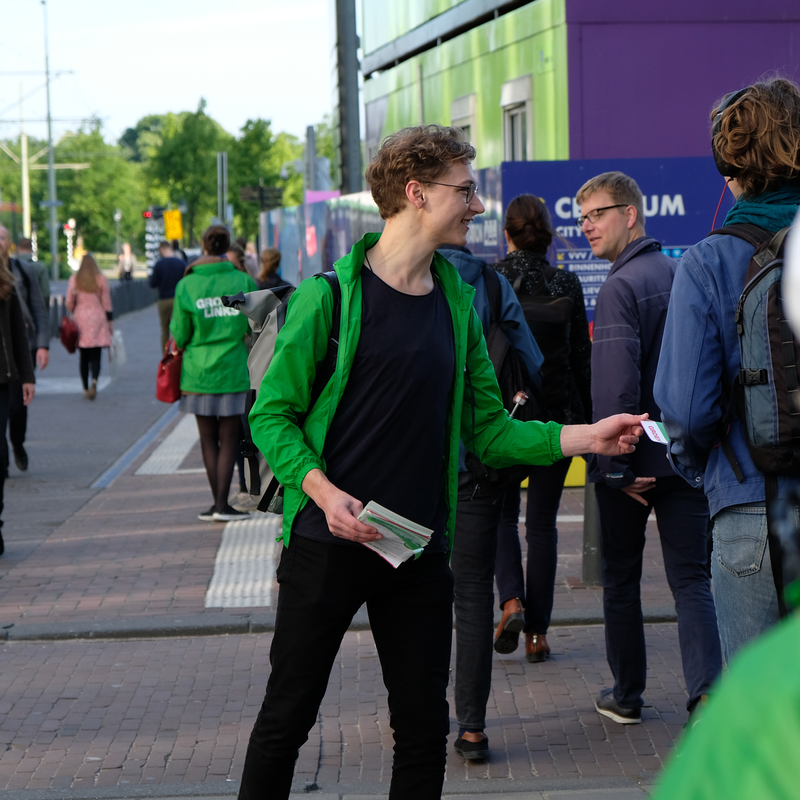 Een GroenLinks-vrijwilliger deelt flyers uit